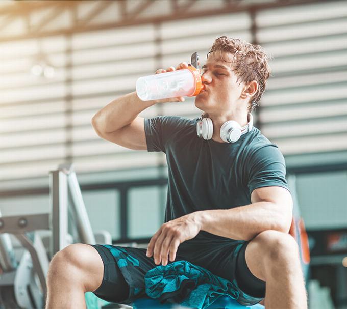 man taking a break from weight lifting to drink protein shake